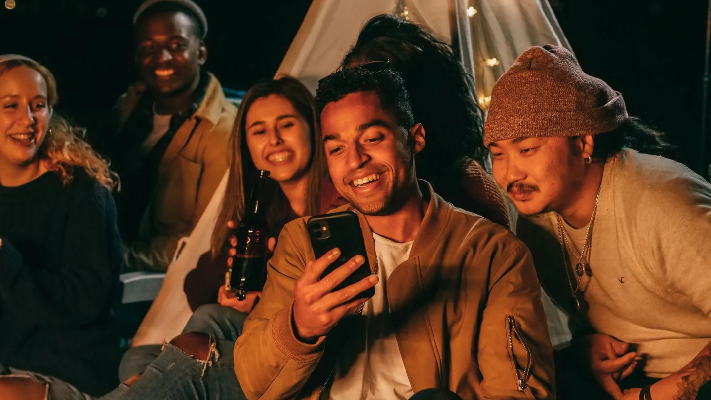 Friends laughing together while sharing something on a phone