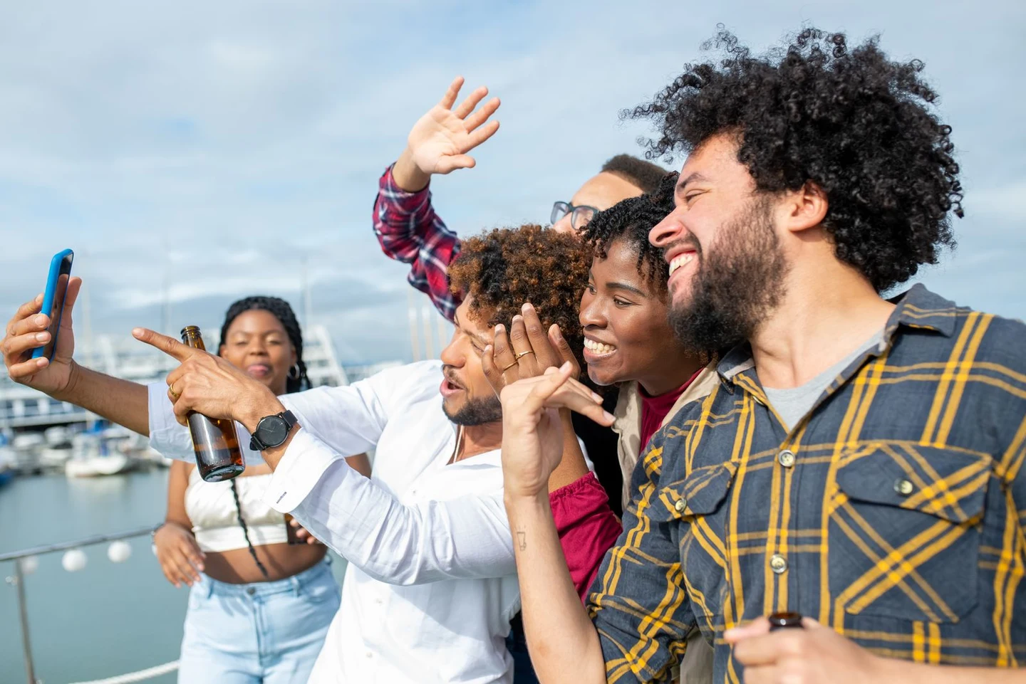 Friends laughing together while taking a selfie by the water